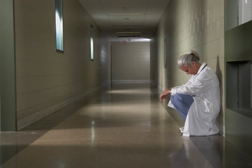 Doctor sitting in hallway looking sad
