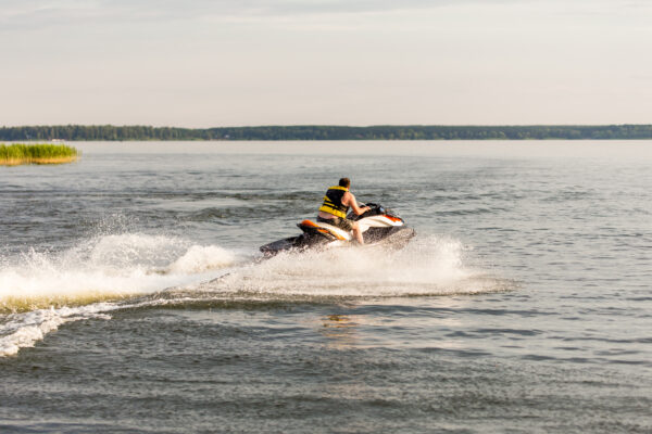 A man driving a jet ski , stunting and making spray of water drops