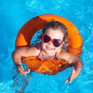 little girl swimming in pool with float and sunglasses