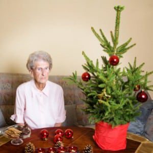 Elderly woman sitting next to Christmas tree