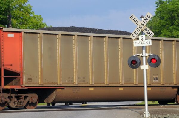 Freight car filled with coal passes over a grade crossing with warning signal